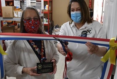 Two women cutting red white and blue ribbon